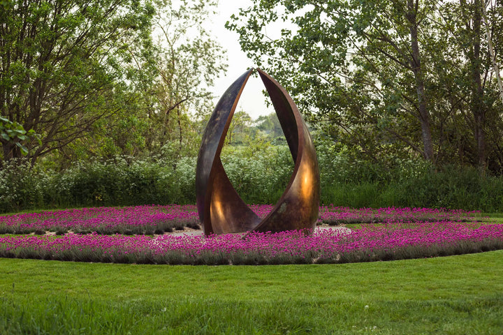 Simon Gudgeon bronze sculpture Embrace featuring monumental abstract curved bronze forms rising upwards and meeting at a central point within a landscaped garden setting.