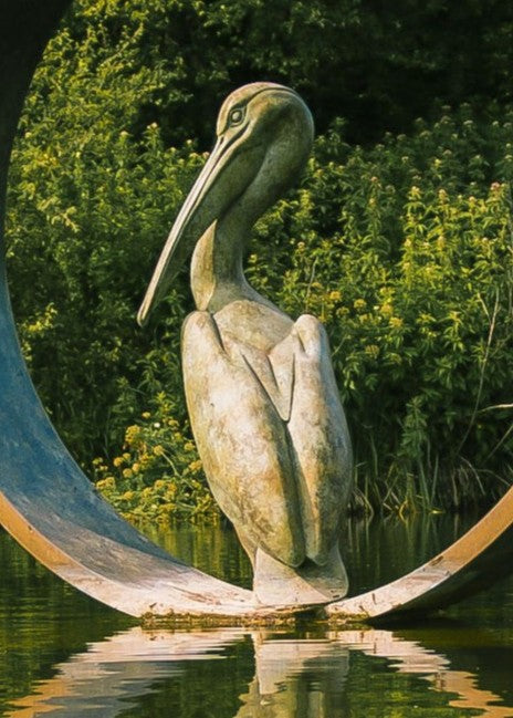 Simon Gudgeon bronze sculpture Pelicans featuring two elegant stylised pelican forms positioned around a circular contemporary bronze structure within a landscaped outdoor setting.