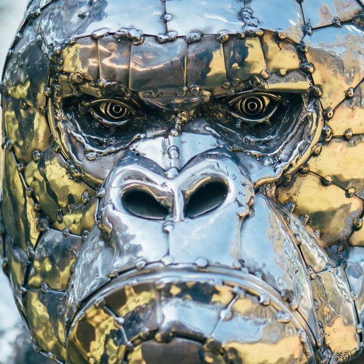 ‘Gorilla’ by Michael Turner, a unique, one-of-one stainless steel wildlife sculpture depicting a powerful silverback gorilla standing on all fours atop a large, dark wooden transport cage. Handcrafted from individually shaped and welded stainless steel panels, the sculpture features a polished silver finish, muscular shoulders, powerful limbs and intricately detailed facial features. The rustic timber cage displays bold white ‘DANGER - HANDLE WITH CARE’ lettering and a metal-barred hatch, adding humour and 