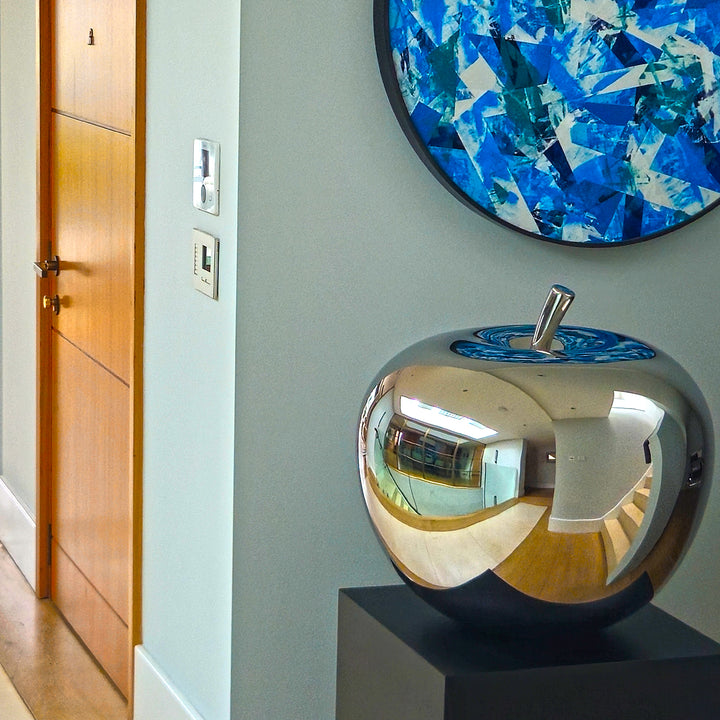 Mirror-polished stainless steel apple sculpture by James Parker, with a smooth reflective surface and softly rounded sculptural form.