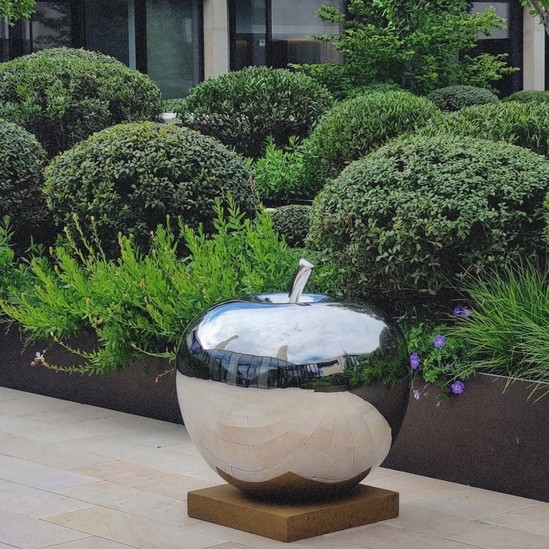 Mirror-polished stainless steel apple sculpture by James Parker, with a smooth reflective surface and softly rounded sculptural form.