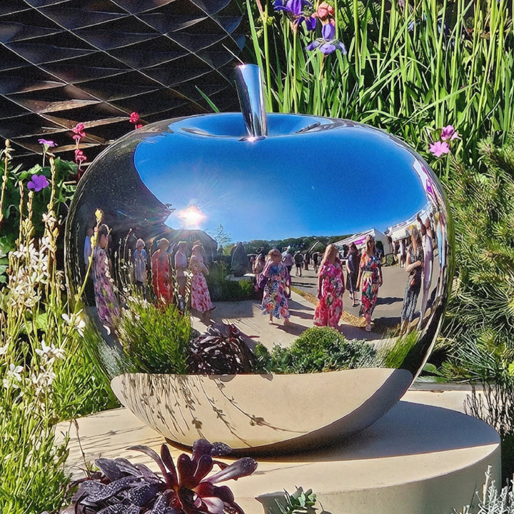 Mirror-polished stainless steel apple sculpture by James Parker, with a smooth reflective surface and softly rounded sculptural form.
