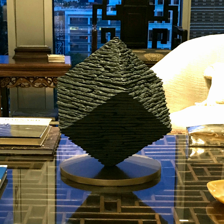 Bronze Cube sculpture by James Parker, balanced on one corner with a layered stacked-slate texture and precise geometric form.