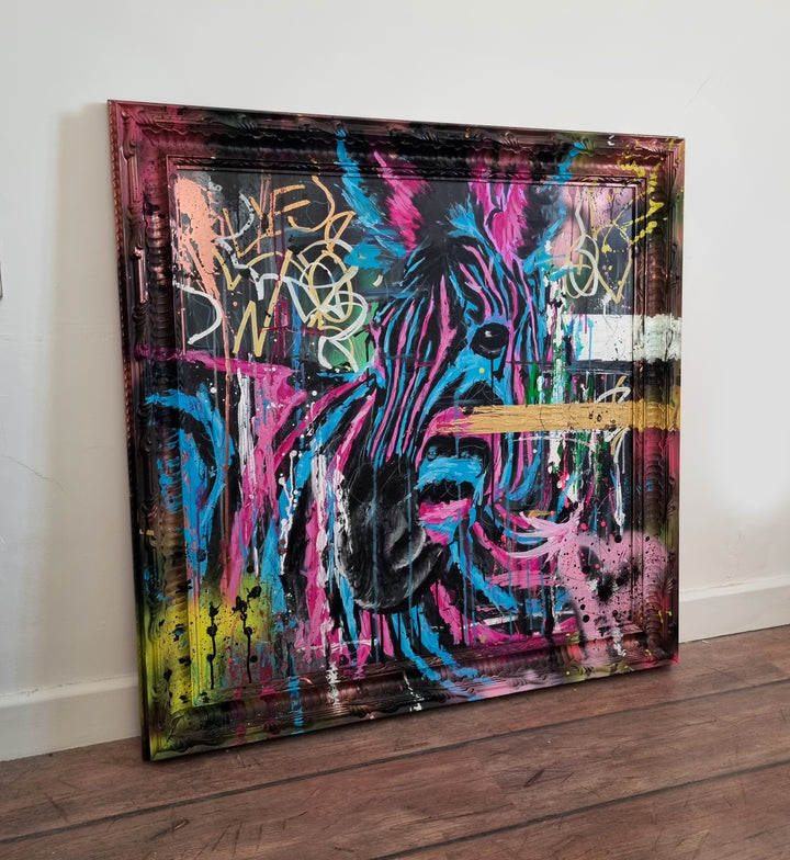 Bold graffiti-style painting of a vibrant zebra titled Equiferus, featuring intense pink, electric blue, black and neon yellow tones, with expressive acrylic and spray paint strokes extending onto a custom-painted ornate frame.