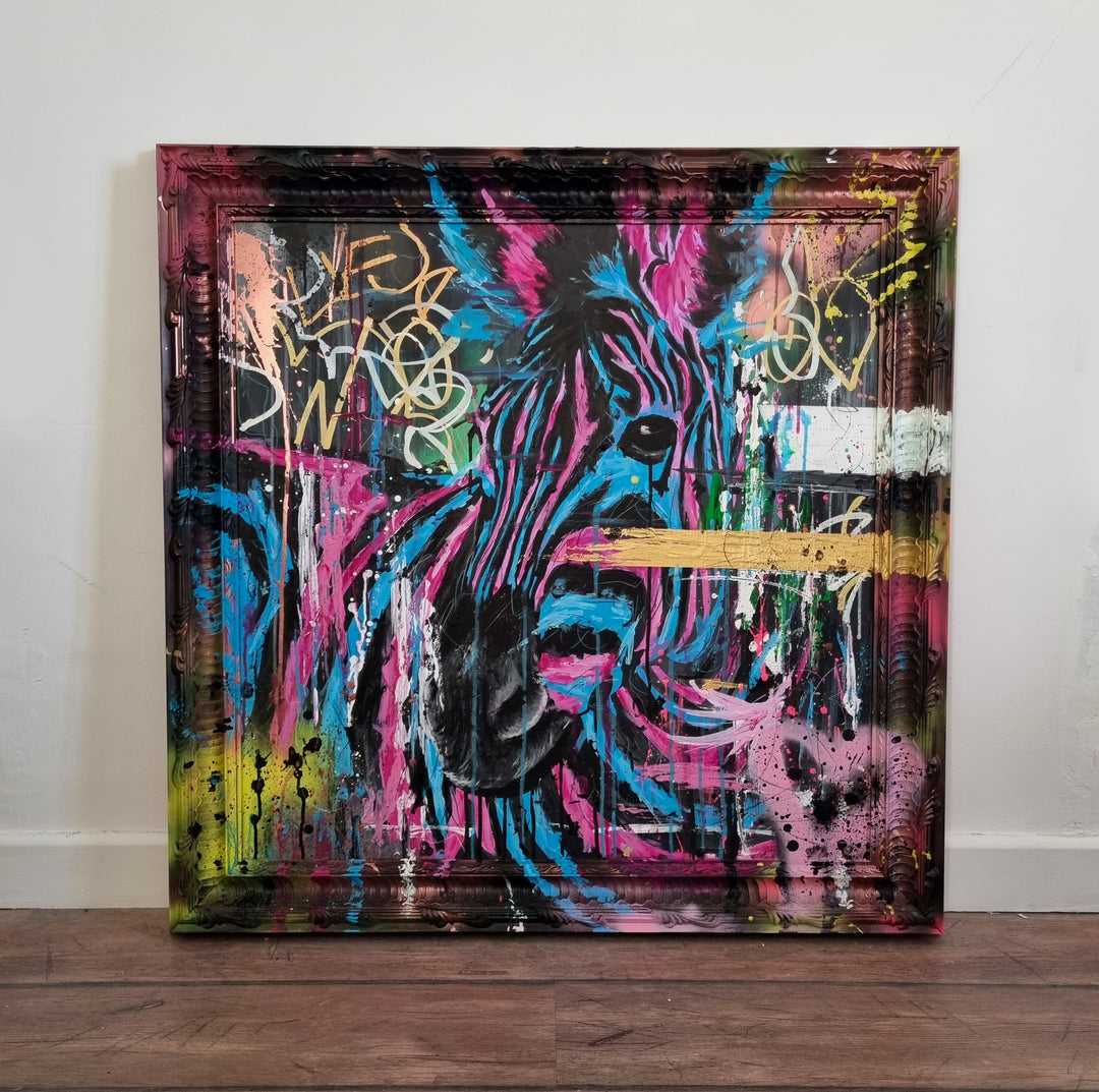 Bold graffiti-style painting of a vibrant zebra titled Equiferus, featuring intense pink, electric blue, black and neon yellow tones, with expressive acrylic and spray paint strokes extending onto a custom-painted ornate frame.