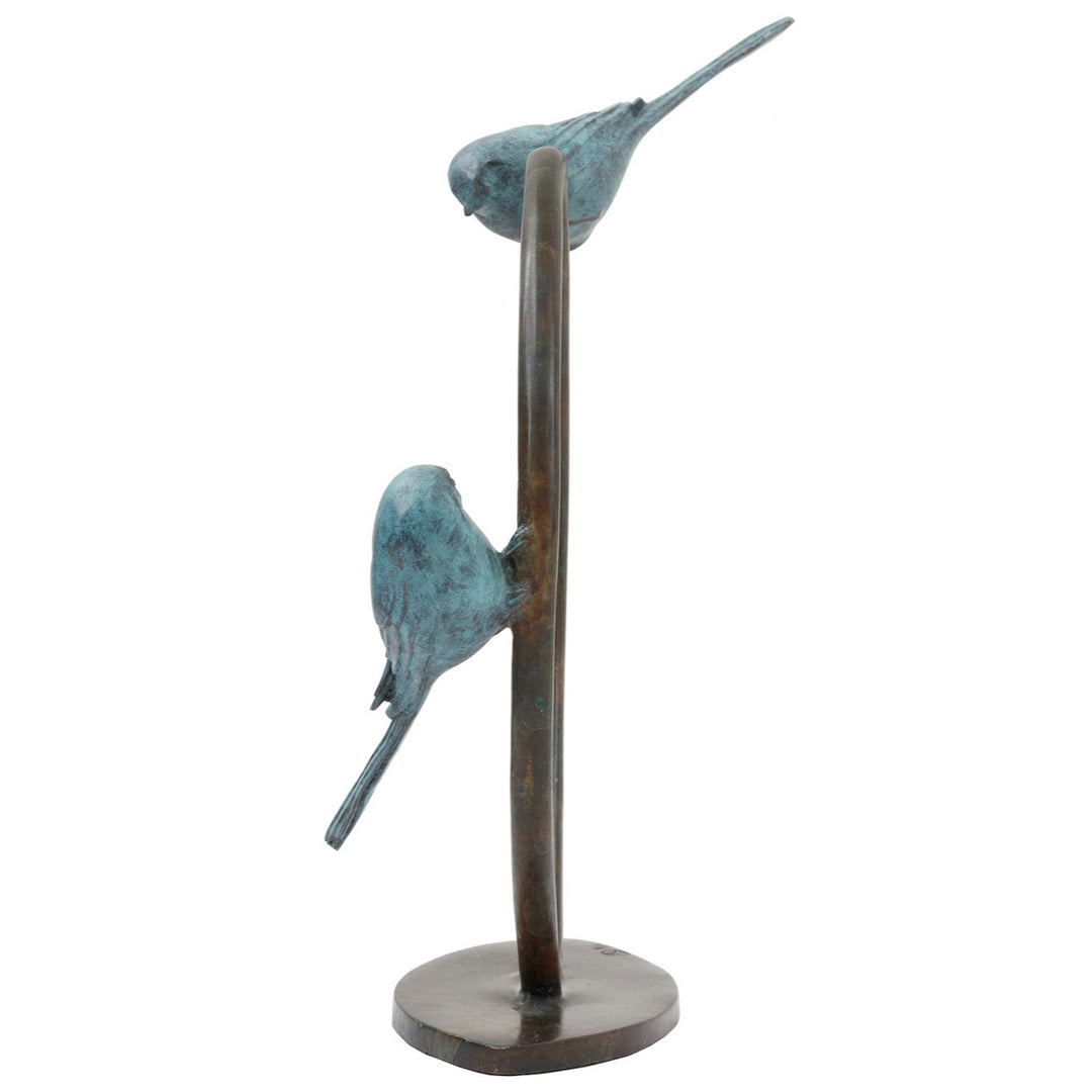 ‘Two’s Company’ by Pat Bull, a limited-edition contemporary bronze wildlife sculpture depicting two long-tailed tits perched on opposite sides of an upright circular bronze ring, facing towards one another. Each bird features a small rounded body, delicate beak, finely textured feathers and an elongated tail, finished in soft turquoise, teal and blue-green verdigris patina. The birds contrast with the dark brown and warm bronze tones of the open ring, which stands on a low oval bronze base against a white b