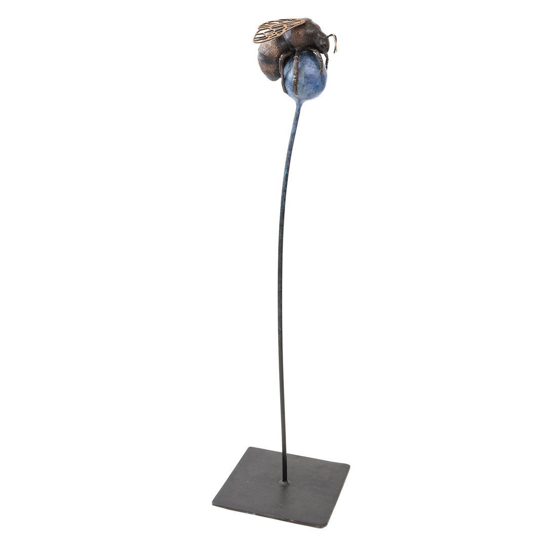 ‘The Bee All and End All’ by Pat Bull, a limited-edition contemporary bronze wildlife sculpture depicting an oversized bumblebee resting on a rounded abstract flower head. The bee features a textured body in dark brown and warm bronze tones, delicate bronze antennae, six detailed legs and intricate openwork wings with polished golden highlights. The spherical flower head is finished in mottled blue, purple and violet patina, supported by a tall, slender steel stem rising from a square dark metal base.