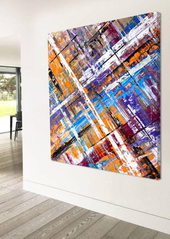 Large abstract painting “Harmonia” by Swarez — layered intersecting lines and blocks in vivid cobalt blue, burnt orange, gold, white and black, with deep royal purple and burgundy undertones. Strong white cross overlay creates depth and structure across a richly textured enamel surface.