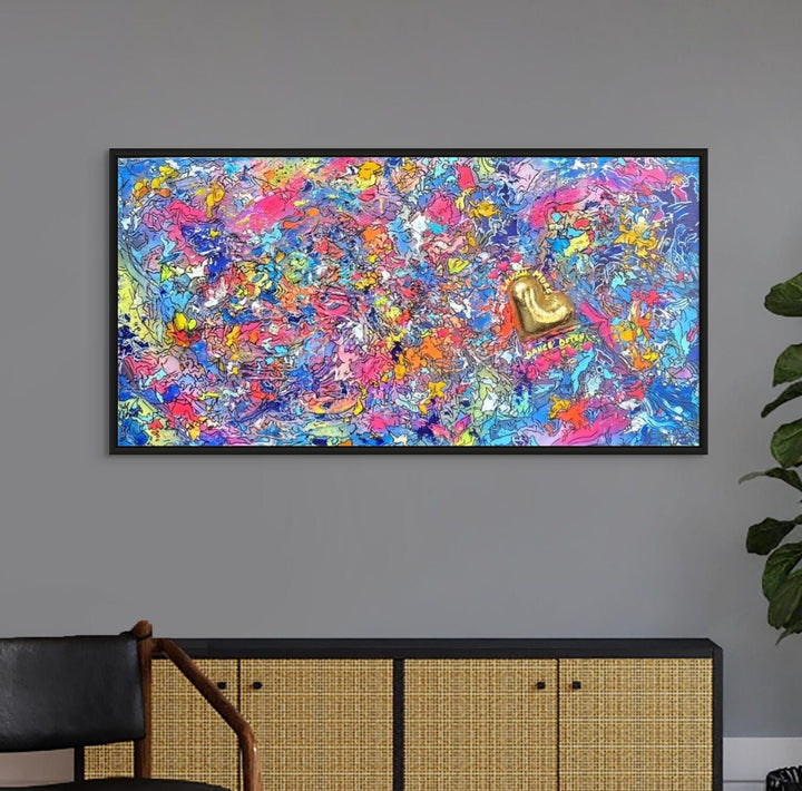 A vibrant abstract mixed-media painting bursting with swirling colours in pink, blue, yellow, orange and purple, with heavy texture and fluid forms. At the right side, a raised gold 3D heart sits prominently with text around it reading “Laugh More, Dance Often”. The artwork has an expressive, energetic surface with layered paint and resin details.