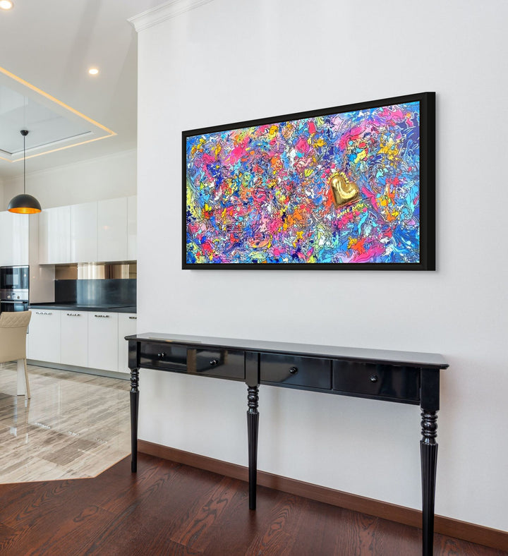 A vibrant abstract mixed-media painting bursting with swirling colours in pink, blue, yellow, orange and purple, with heavy texture and fluid forms. At the right side, a raised gold 3D heart sits prominently with text around it reading “Laugh More, Dance Often”. The artwork has an expressive, energetic surface with layered paint and resin details.