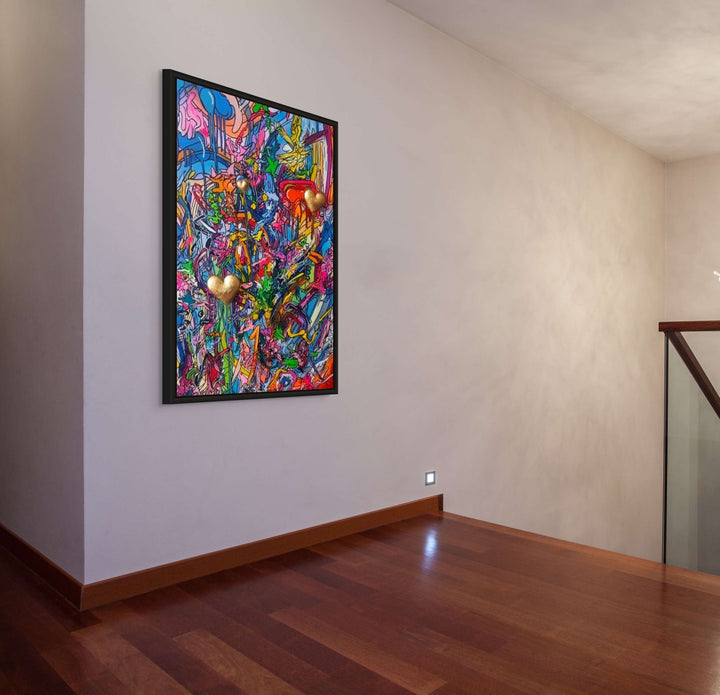 A vibrant mixed-media abstract artwork filled with layered graffiti-style lines, drips and splashes in bright pinks, blues, yellows and greens, featuring three raised gold 3D heart elements floating within the composition, framed in a black tray frame.