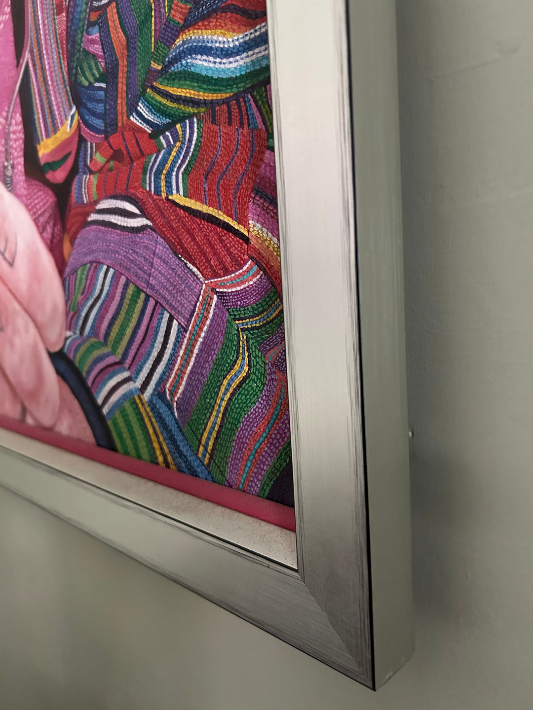 Mick by James Earley — a hyperrealist oil painting of an elderly homeless man in a colourful patchwork jacket and Union Jack bucket hat, staring directly at the viewer with blue eyes full of depth and resilience, his knuckles spelling “LOVE.” Behind him, cardboard signs and childhood photos evoke themes of loss, survival, and invisible trauma.