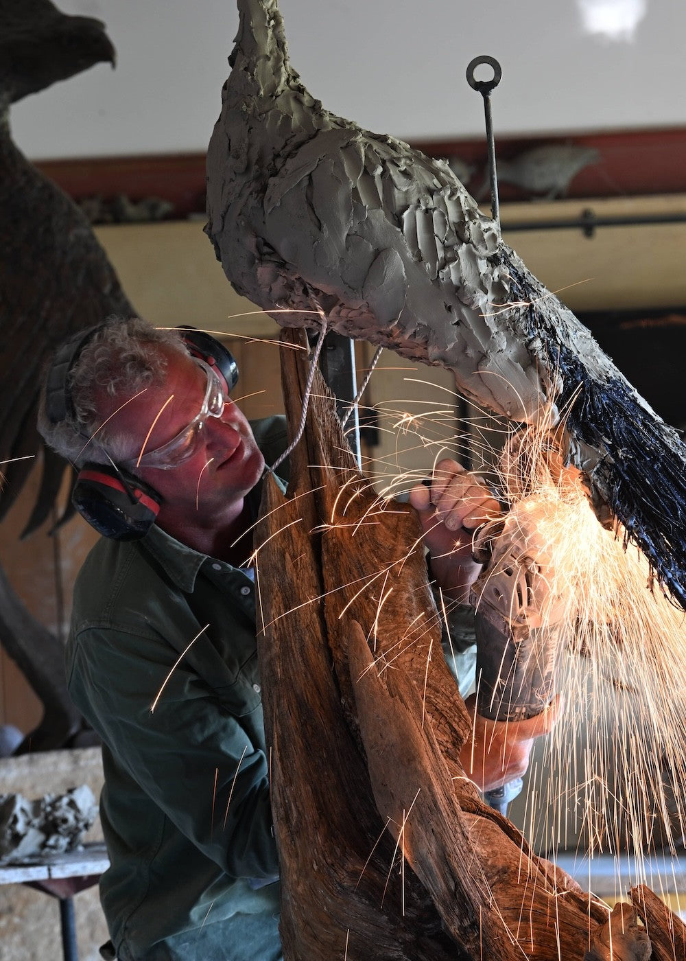 ‘Peacock Life Size’ by Hamish Mackie, a life-size limited-edition bronze bird sculpture depicting a majestic peacock standing upright on an ancient, weathered tree root. The sculpture features an elegant neck, finely textured plumage and an exceptionally long, folded tail cascading towards the ground. Finished in dark, natural bronze with intricate feather detailing, this contemporary wildlife sculpture captures the distinctive form and presence of a peacock.