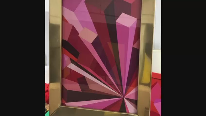 Rob Wyn Yates Metropolis – geometric abstract painting in vivid shades of pink, red, burgundy, and magenta, radiating from a central point with bold angular forms, set in a polished 1970s brass frame.