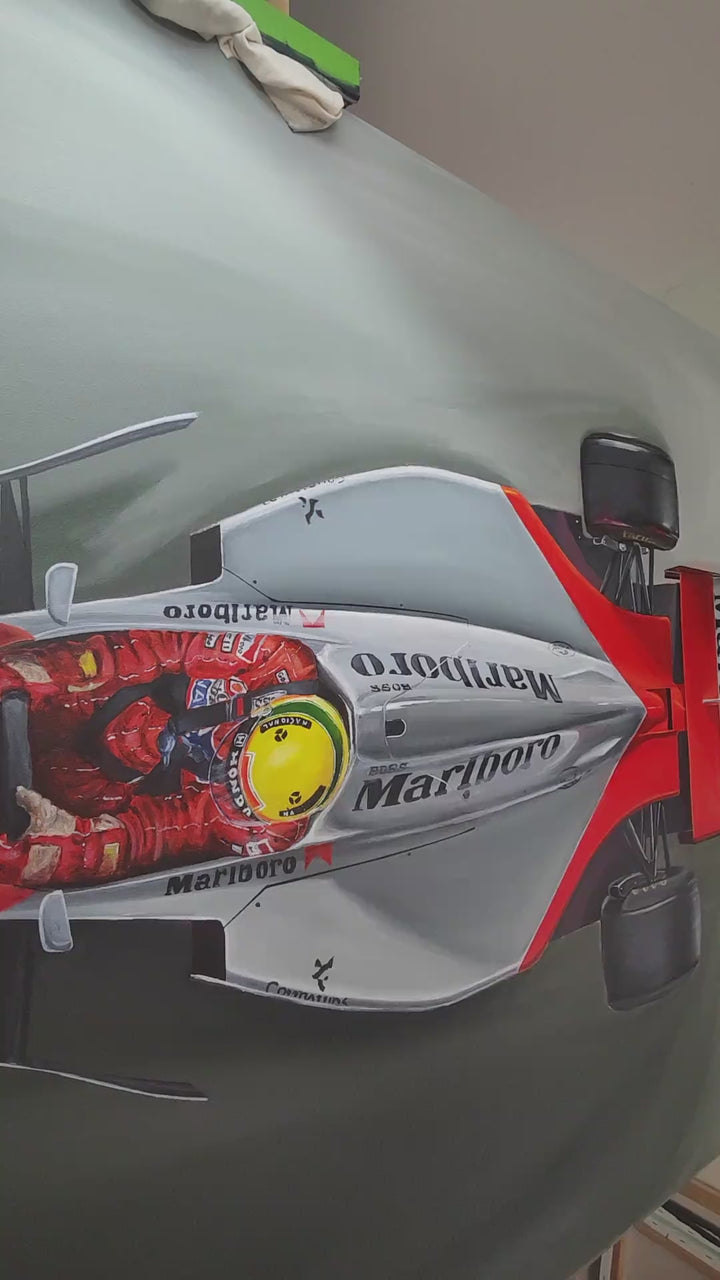 Video of Hyper-realistic top-down painting of Ayrton Senna driving the legendary McLaren MP4/4 Formula 1 car, finished in iconic Marlboro red and white livery, set against a deep grey racing track background. Senna’s bright yellow helmet glows at the centre of the sleek aerodynamic body, capturing speed, control, and motorsport heritage in a striking aerial perspective.