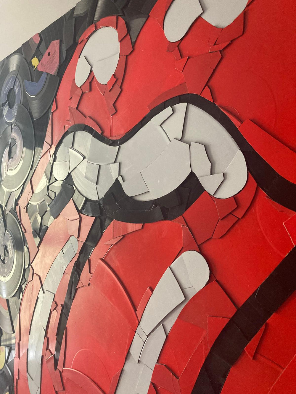 Ed Chapman mosaic of the Rolling Stones’ iconic tongue and lips logo, meticulously crafted from broken original Rolling Stones vinyl records in striking red, black, and white tones.