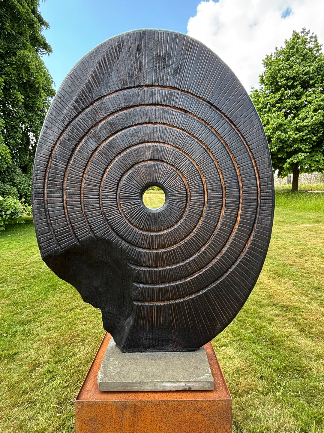 Charred oak sculpture by Glen Farrelly titled Ritual, carved with concentric cup and ring markings around a central void. Blackened Yakisugi surface contrasts with golden highlights, evoking ancient standing stones and ritual energy.