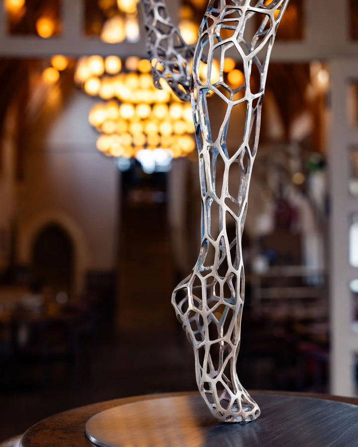 ‘Parallel Passé’ by Simon Gudgeon, a limited-edition figurative bronze sculpture inspired by Prima Ballerina Ksenia Ovsyanick. The life-size female dancer is captured en pointe in an elegant, dynamic ballet pose, formed through an intricate open Voronoi lattice that allows light and the surrounding environment to pass through and transform the sculpture.