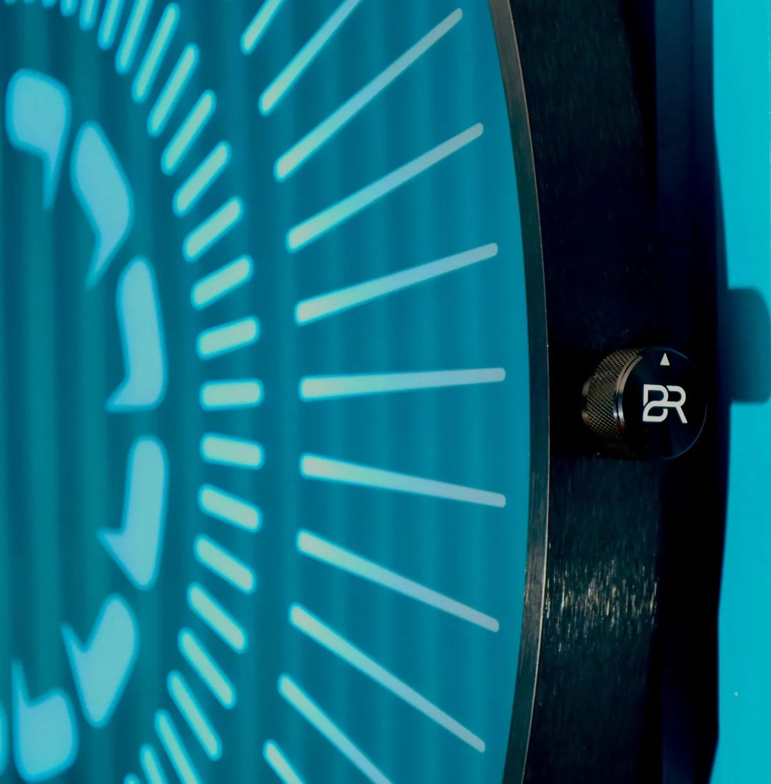 “Tempus Obsidian” by Ben Rousseau – a limited-edition illuminated wall timepiece crafted from grey mirrored glass and brass-tinted aluminium with LEDs. Inspired by obsidian, it radiates calm through subtle light and refined design.

